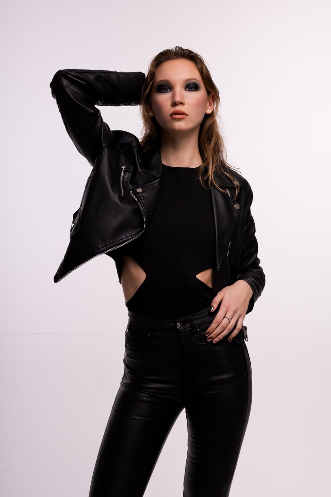 Model in black clothing and a leather jacket against a light studio background